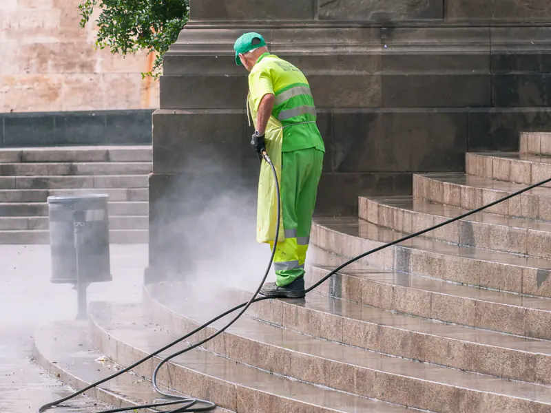 Worker pressure-washing wide stone steps