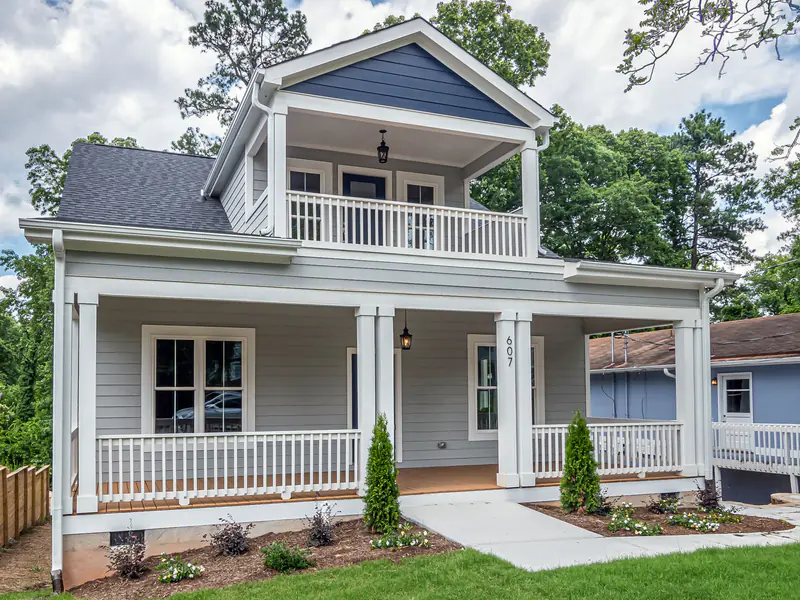 White two-story house with a covered front porch, columns and railings