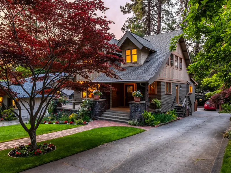 Craftsman house with a red maple in the front yard at dusk