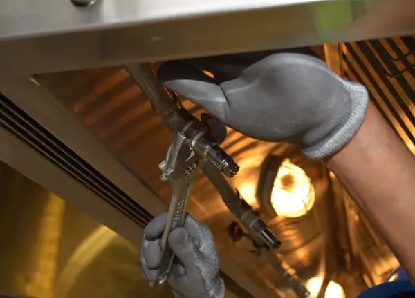 Gloved hands tightening pipe joints with a wrench