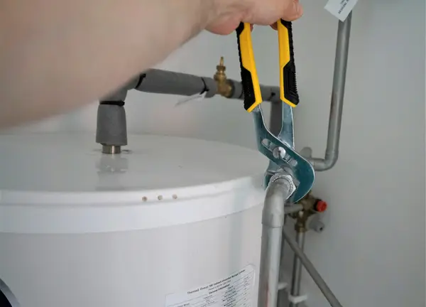 Pliers on a pipe fitting at the top of a water heater