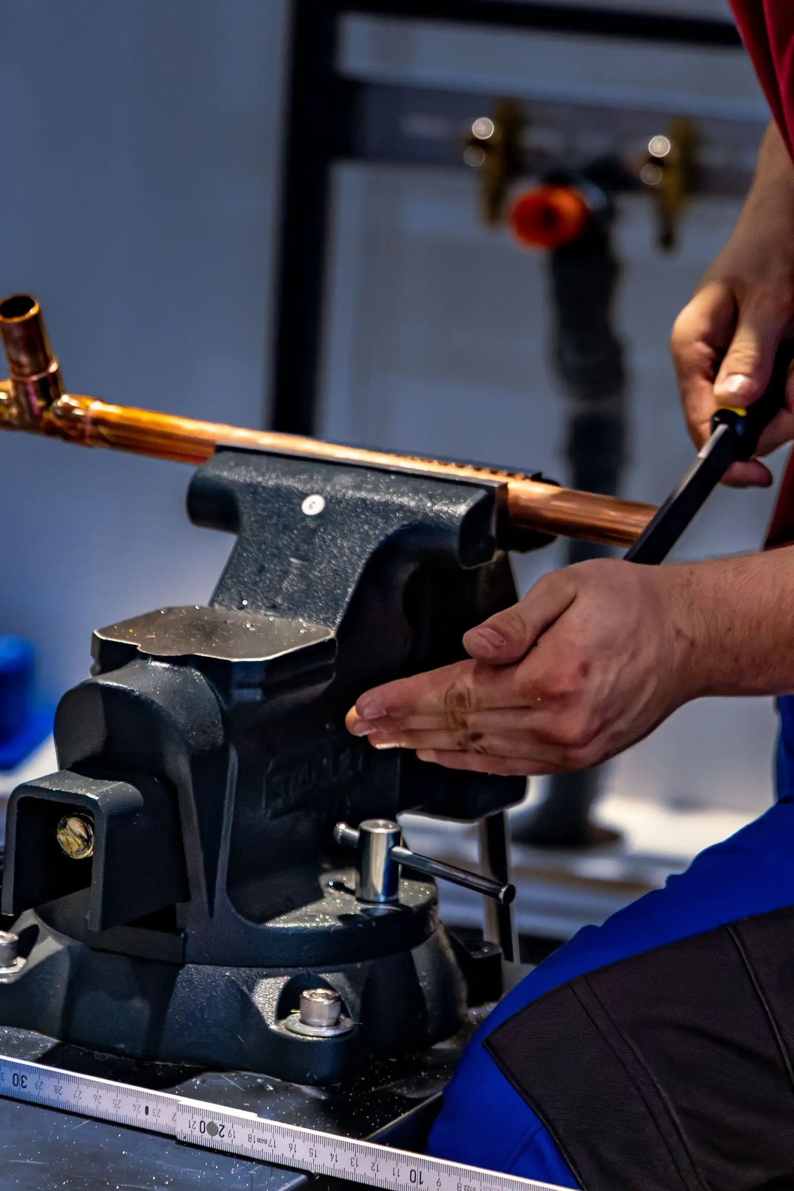 Plumber cutting copper pipe held in a vise